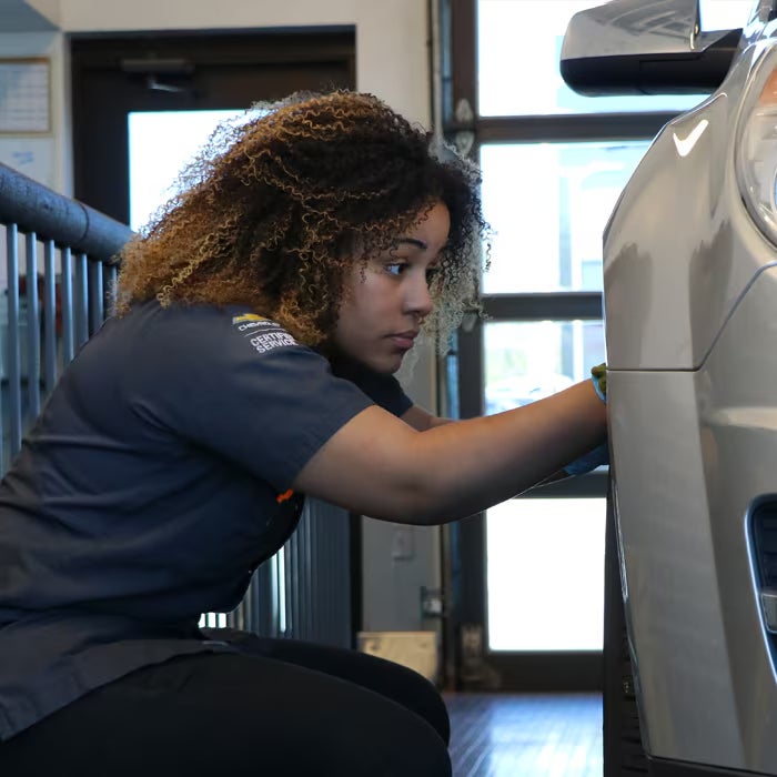 Automotive service technician conducting a detailed vehicle inspection in a service center.